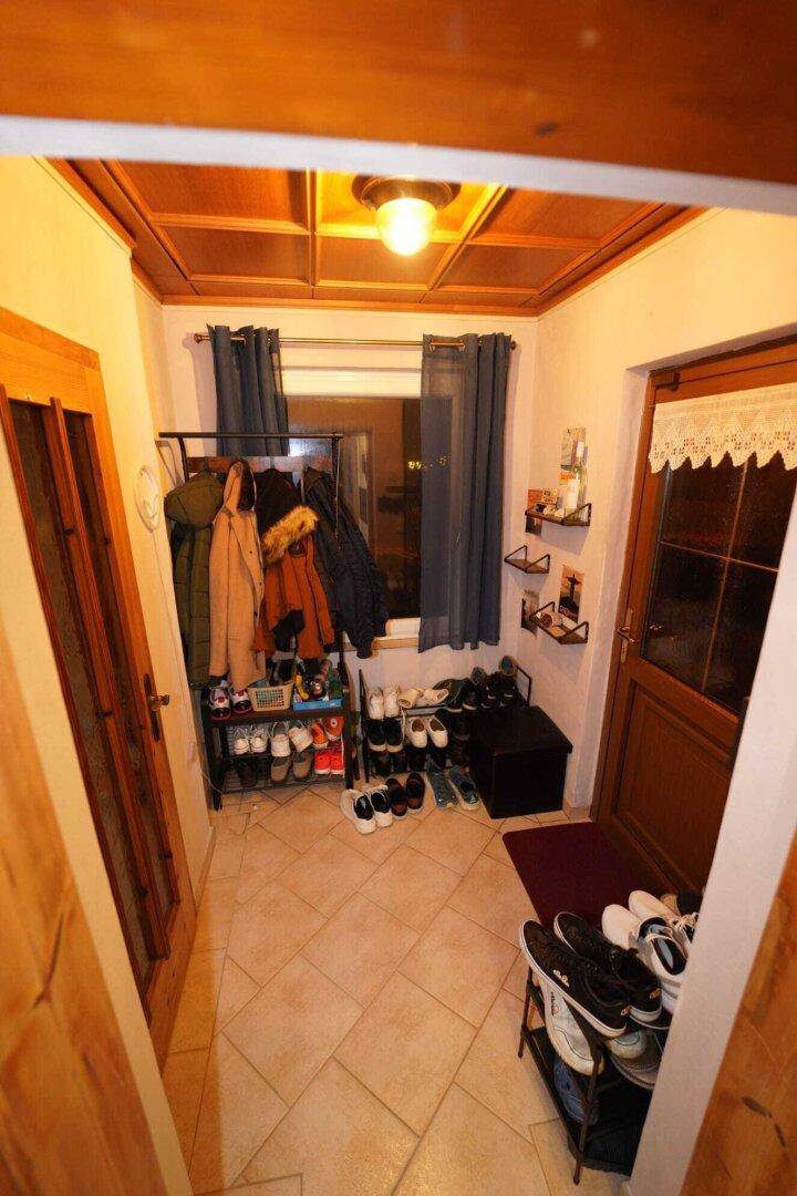 Ein Eingangsbereich mit Fliesenboden, Holzdecke und viel Stauraum für Schuhe und Jacken.