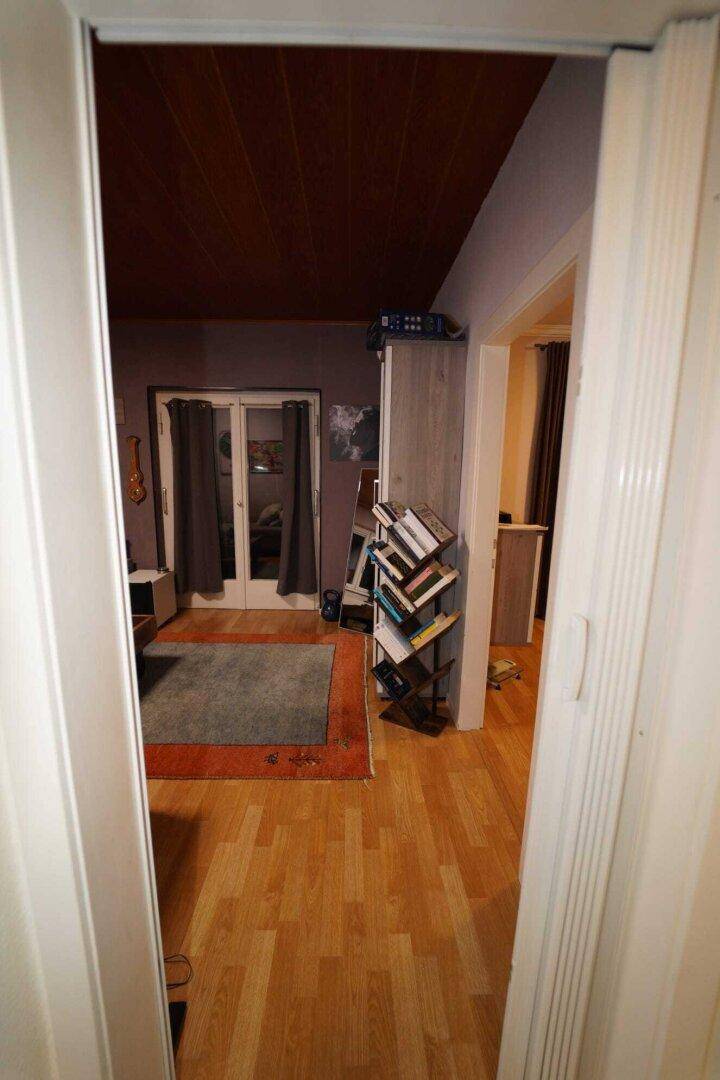 Durchgang zu einem Wohnbereich mit Holzdecke und Parkettboden.