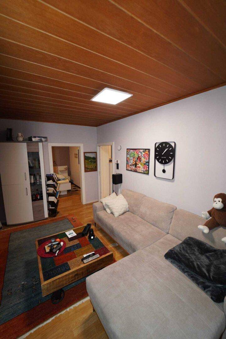 Helles Wohnzimmer mit Holzboden, bequemer Eckcouch und moderner Dekoration an den Wänden.