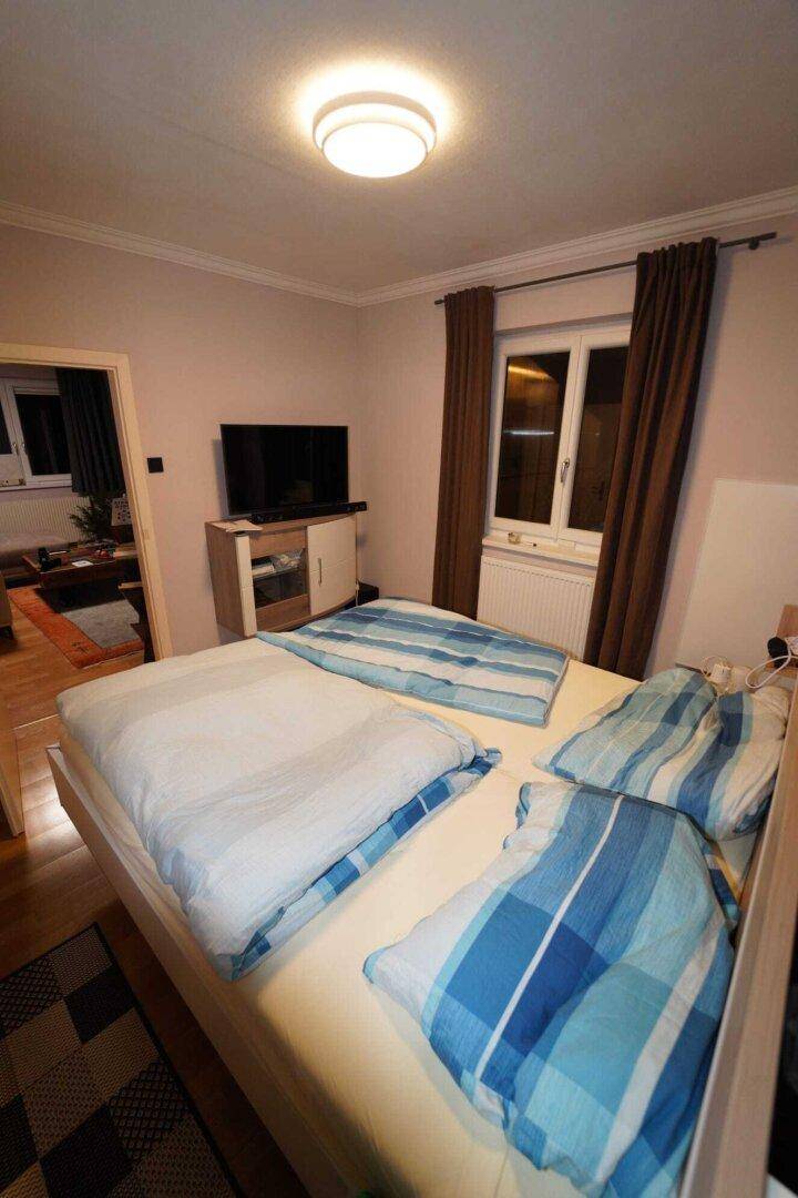 Schlafzimmer mit Doppelbett, Holzdecke, Parkettboden und Fenster.