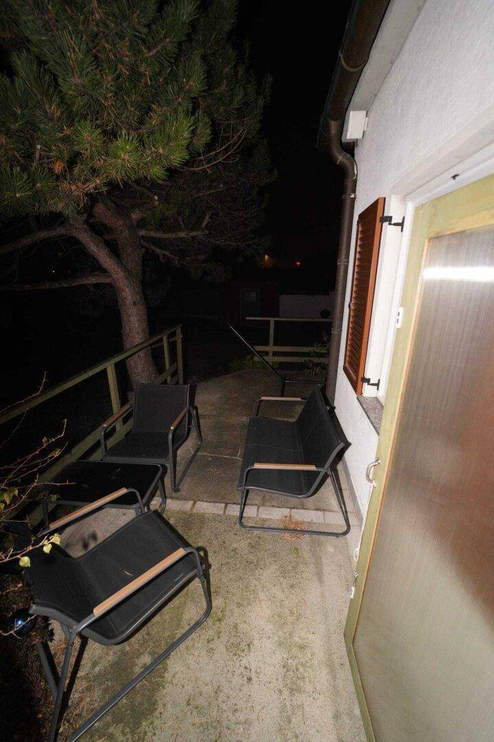 Gemütliche Terrasse am Abend mit Gartenmöbeln und umgebender Natur.