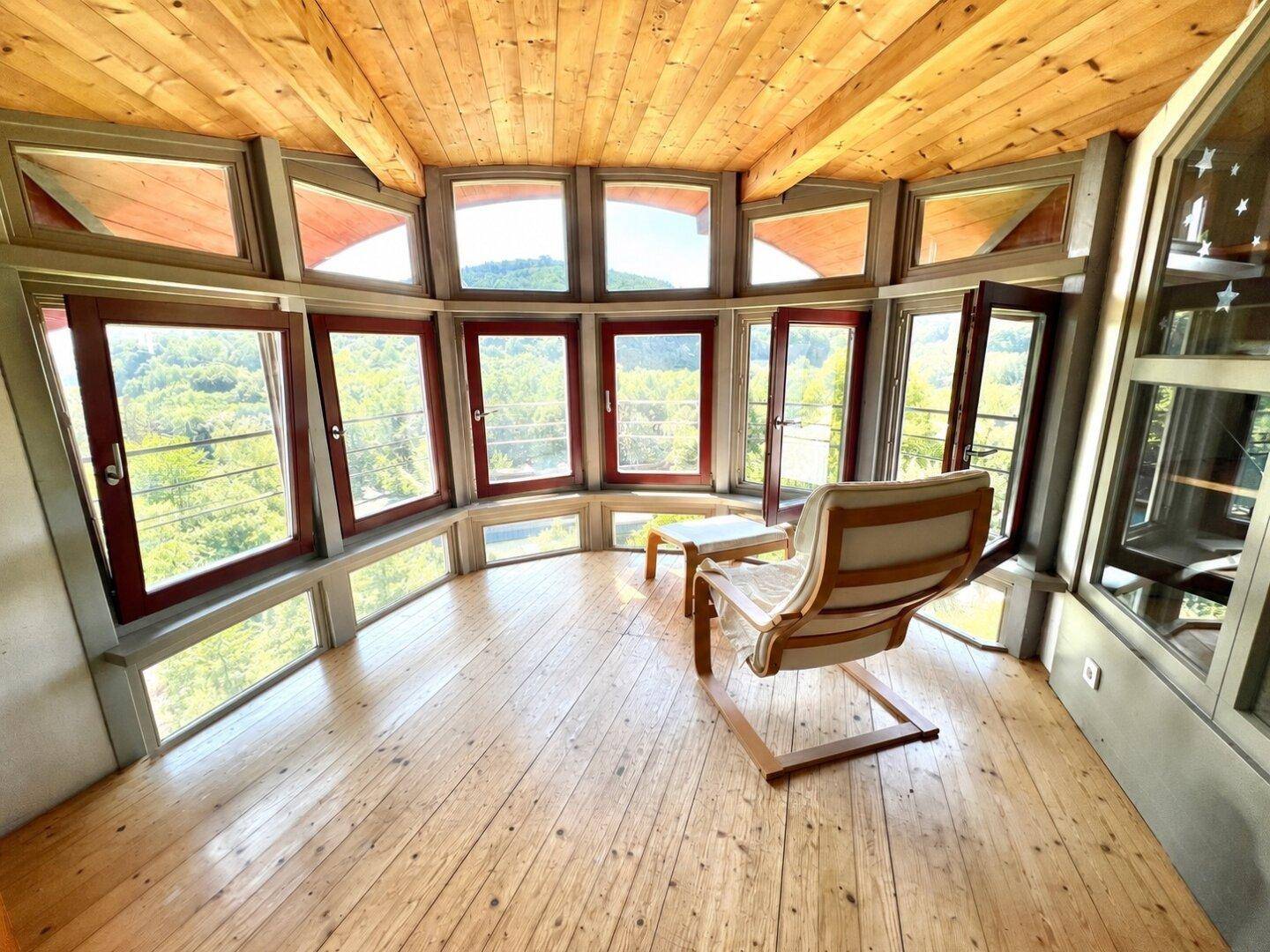 Einzigartiger Raum im Glasturm mit Holzboden und atemberaubendem Panoramablick auf die Natur.