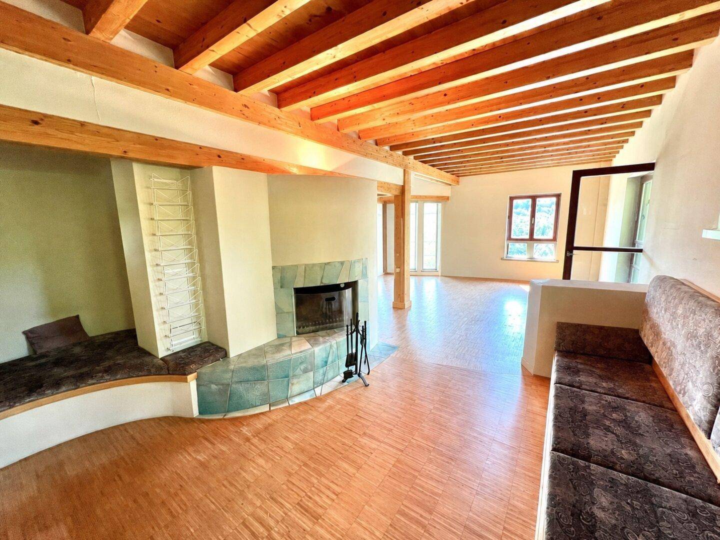 Gemütlicher Wohnbereich mit Holzbalkendecke, Kachelofen und integrierten Sitzgelegenheiten.