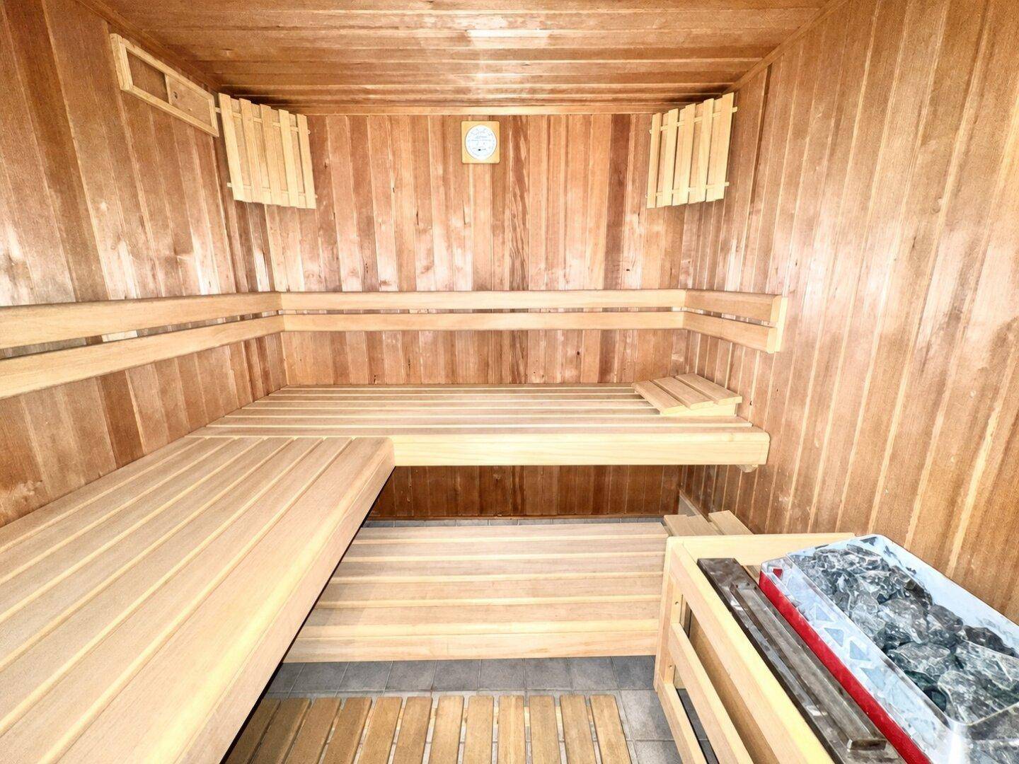 Traditionelle Holzsauna mit mehreren Bänken und einem Saunaofen für Entspannung.