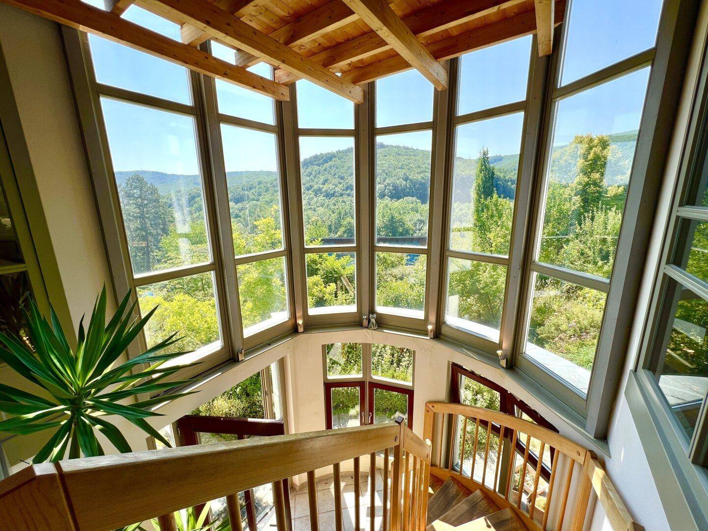 Beeindruckendes Treppenhaus in einem Glasturm mit Panoramablick auf die grüne Landschaft.