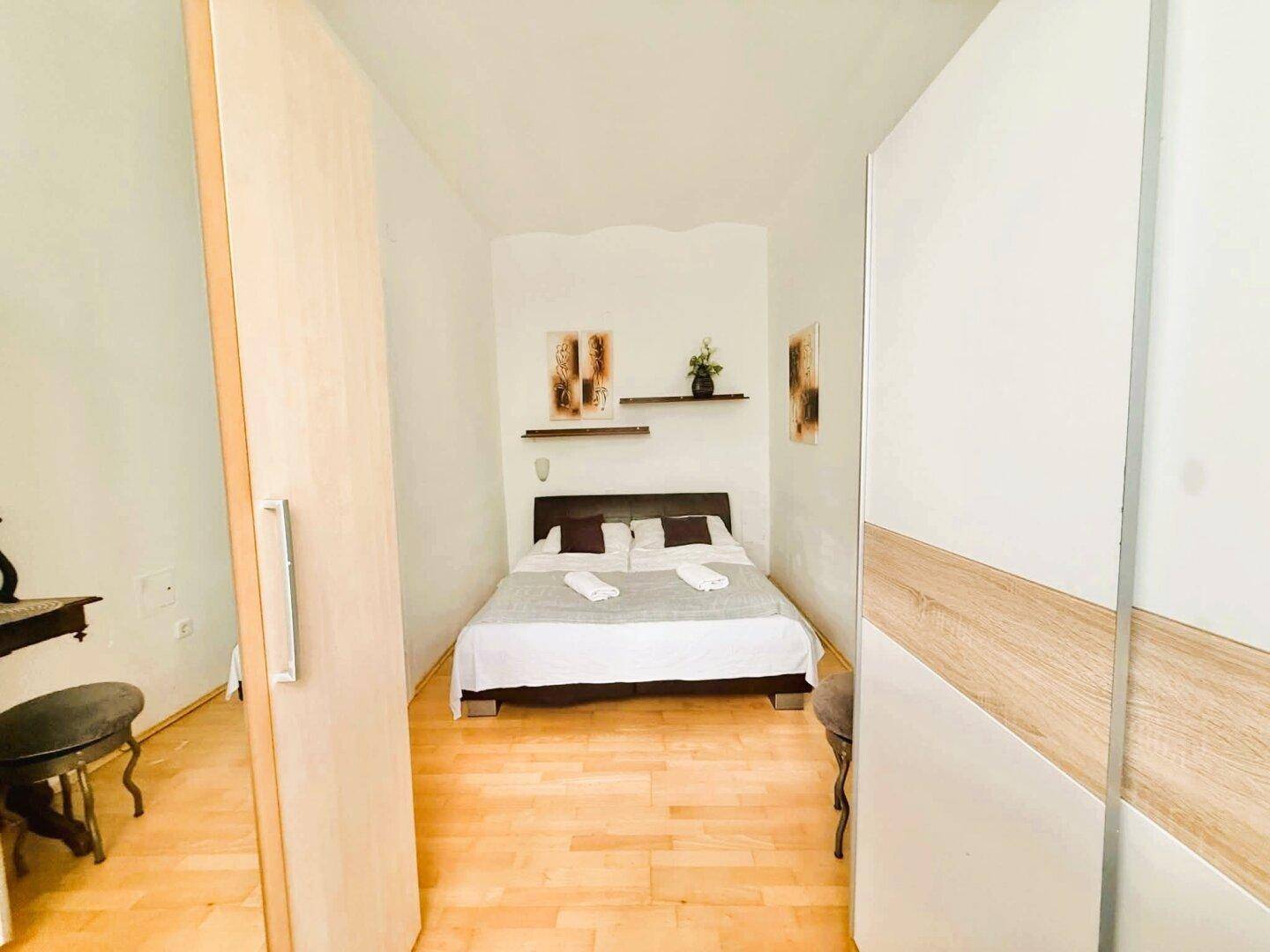 Schlafzimmer mit Holzboden, Doppelbett und einem modernen Kleiderschrank.