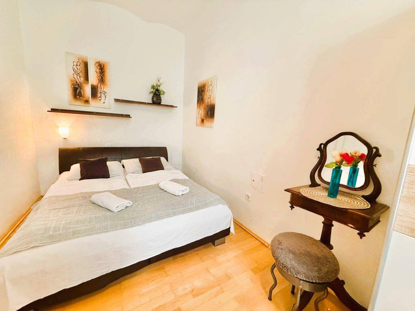 Gemütliches Schlafzimmer mit Holzboden, Doppelbett und einem eleganten Schminktisch.
