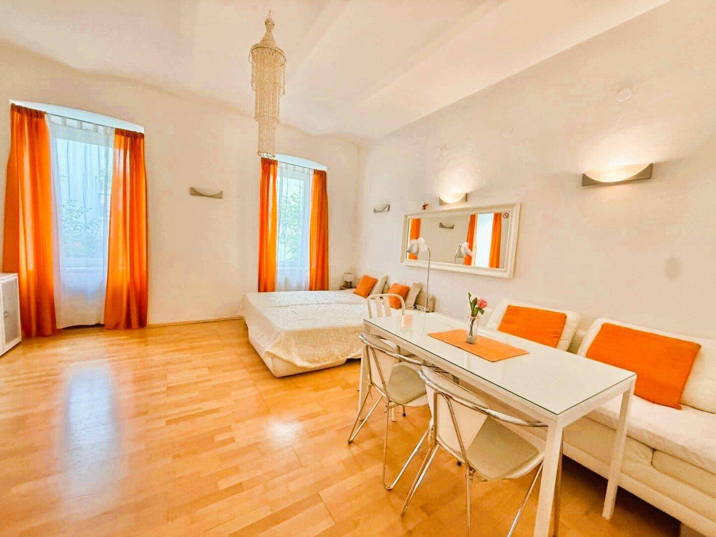 Geräumiges Wohnzimmer mit Holzboden, Essbereich und großen Fenstern für viel Licht.
