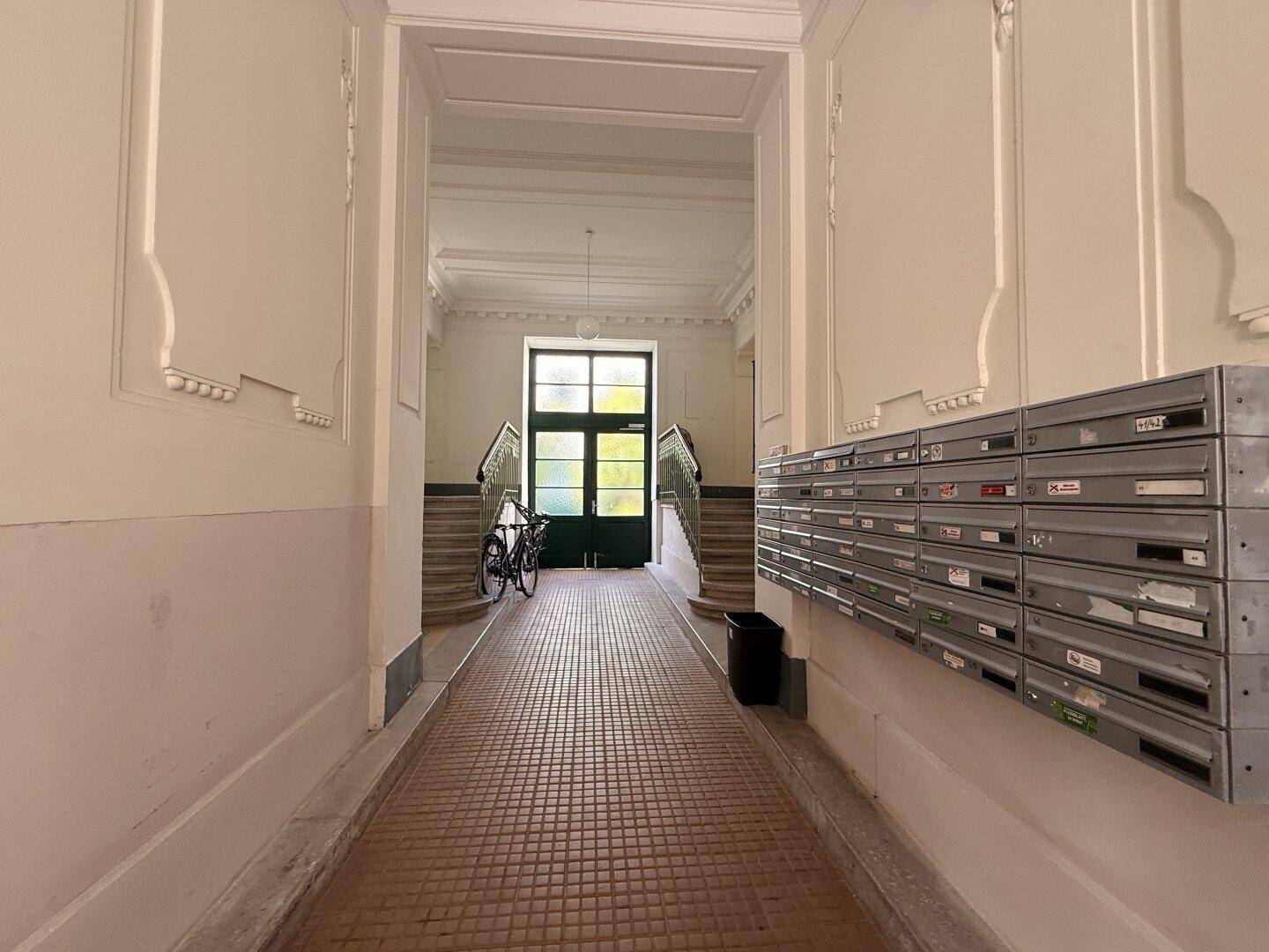 Eingangsbereich mit Briefkästen, Treppe und Zugang zum Gebäudeinneren.