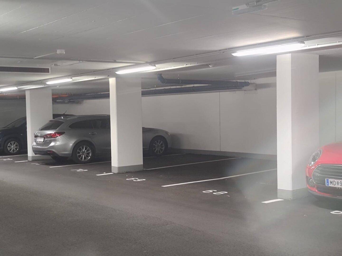 Mehrere Tiefgaragenstellplätze in einer modernen und gut beleuchteten Tiefgarage mit verschiedenen Fahrzeugen.
