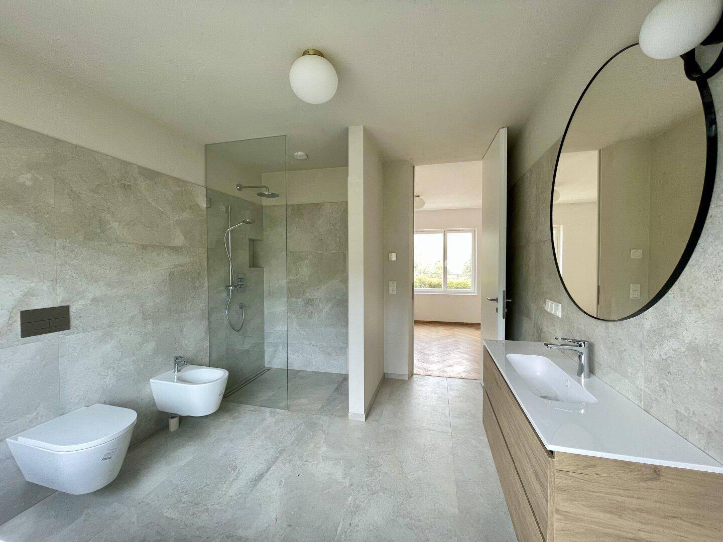 Elegantes Badezimmer mit großer begehbarer Dusche, Bidet und modernem Waschtisch.