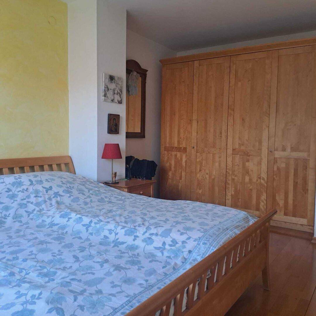Schlafzimmer mit Doppelbett, Holzboden und großem Einbauschrank aus hellem Holz.