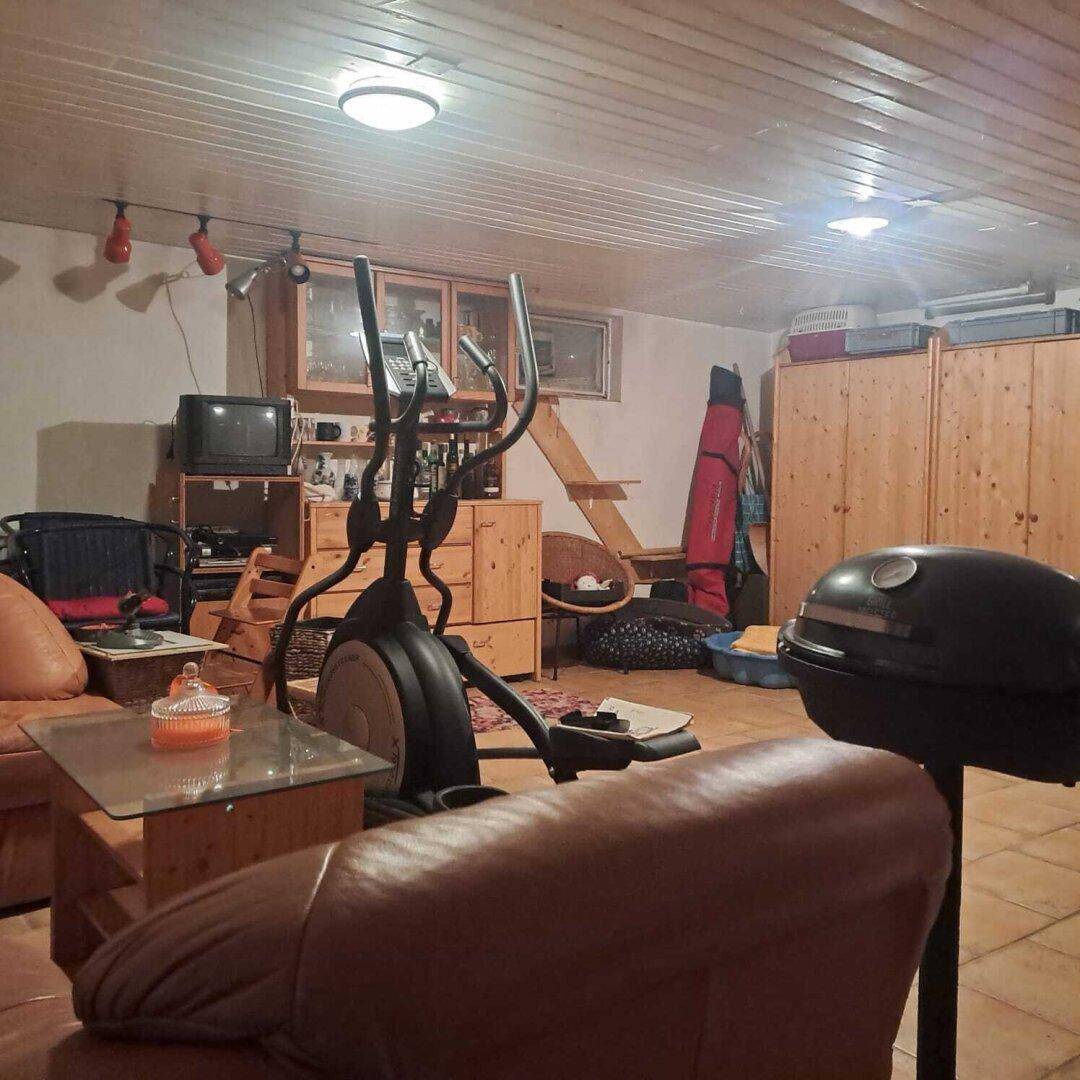 Vielseitiger Kellerraum mit Fitnessgeräten, Sitzgelegenheiten und Stauraum.