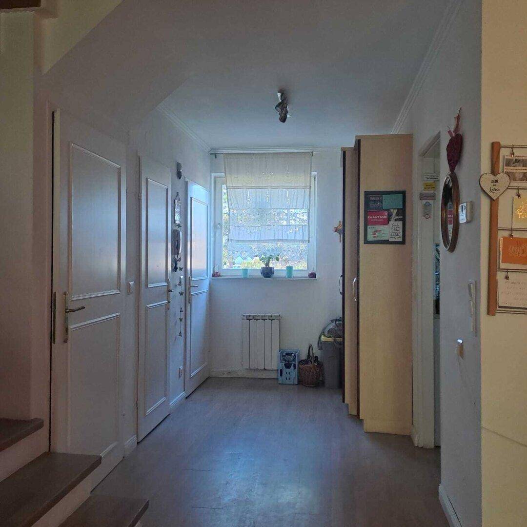 Heller Flur mit Fenster, Einbauschränken und Zugang zu weiteren Räumen im Haus.