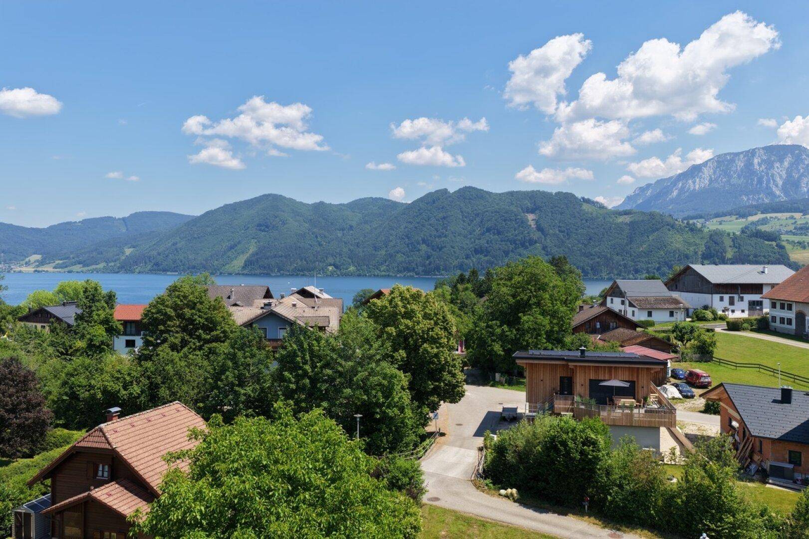 Panoramablick auf den See und die umliegende Berglandschaft mit Häusern.