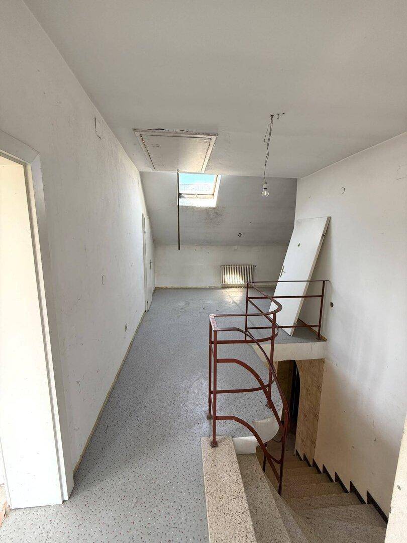 Treppenhaus mit Dachfenster und Zugang zu weiteren Räumen, bereit zur Renovierung.