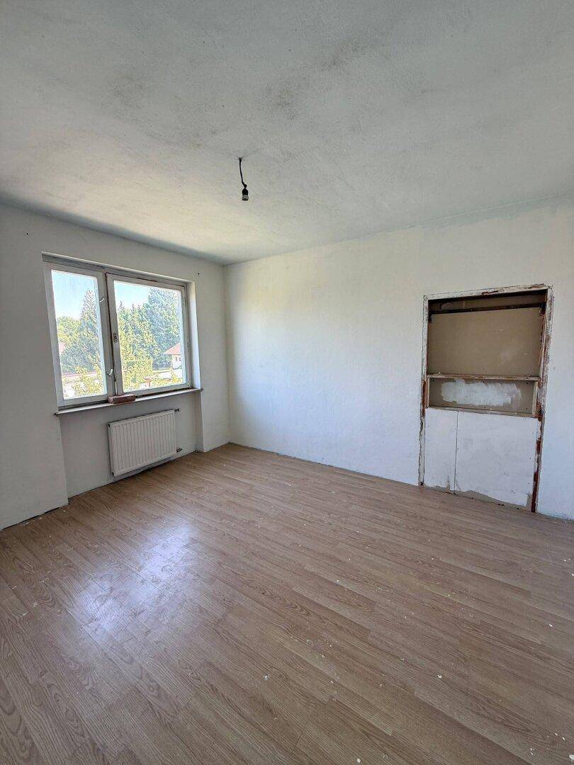 Leeres Schlafzimmer mit Holzboden und Fenster, bereit zur individuellen Gestaltung.