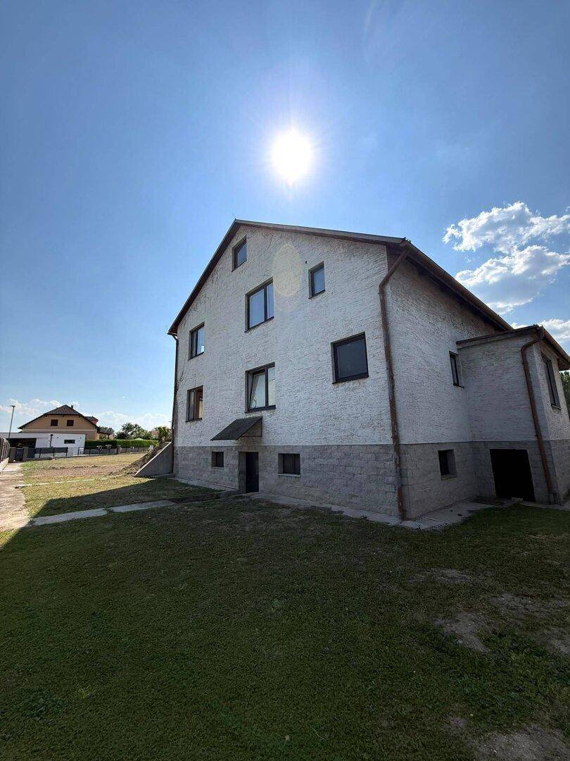 Seitenansicht des Hauses mit Gartenbereich und sonnigem Himmel.