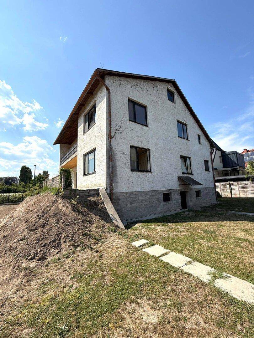 Seitenansicht des Einfamilienhauses mit Garten und angrenzendem Grundstück.