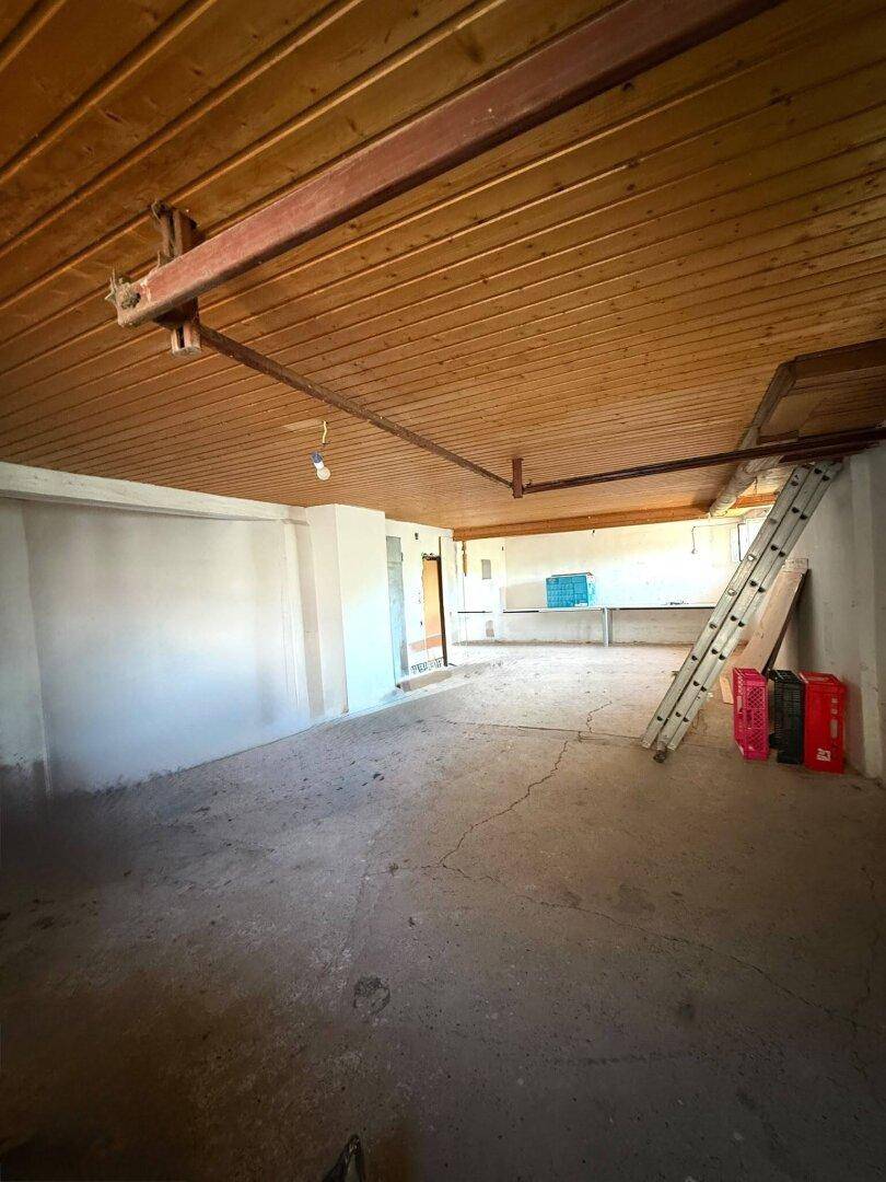 Geräumiger Kellerraum mit Holzdecke und Betonboden, ideal als Werkstatt oder Lager.