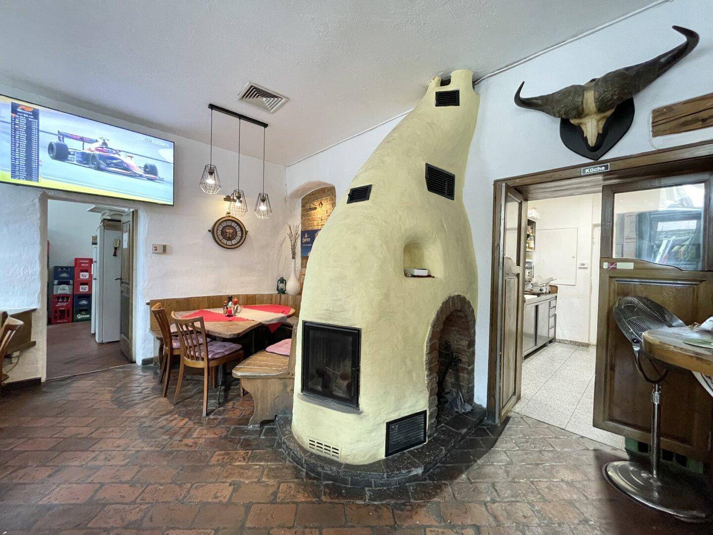 Gemütlicher Restaurantbereich mit einem großen Kamin, rustikalen Holzmöbeln und einem Fernseher an der Wand.