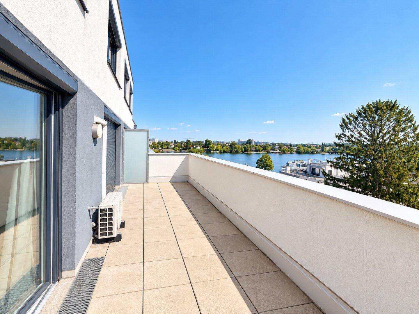Langer Balkon mit Fliesenboden und weitem Blick auf den See und die Umgebung.