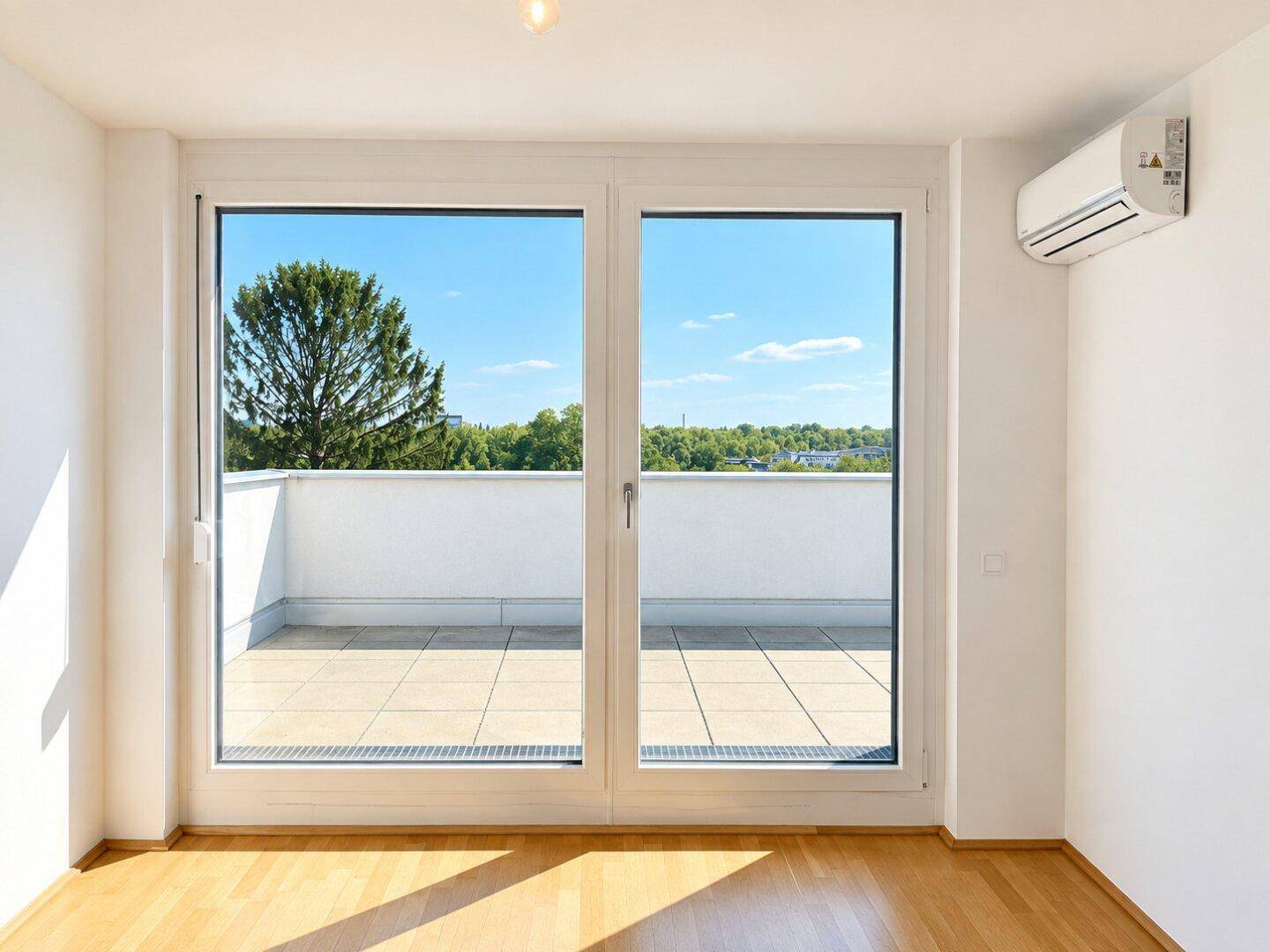 Helles Zimmer mit Parkettboden, Klimaanlage und Zugang zu einer großen Terrasse.