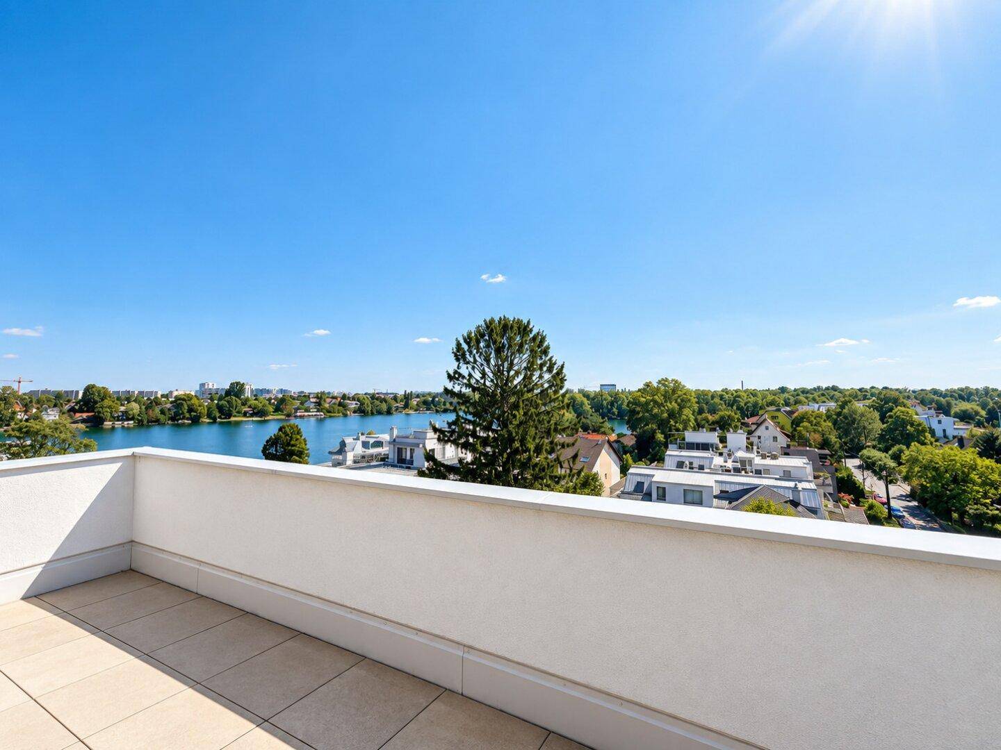 Sonniger Balkon mit Fliesenboden und Panoramablick auf den See und die grüne Landschaft.