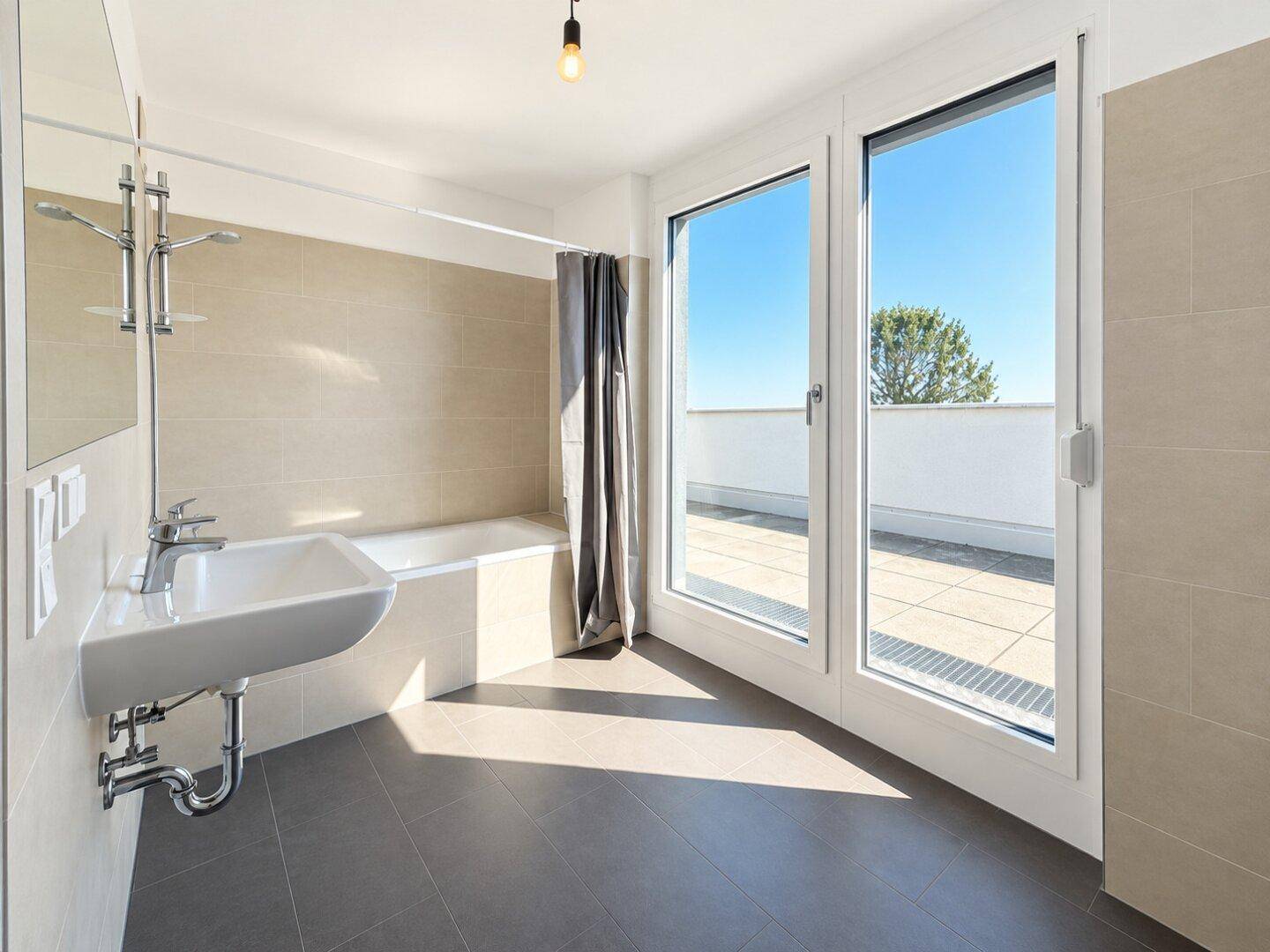 Modernes Badezimmer mit Badewanne, Waschbecken und Zugang zu einer Terrasse.