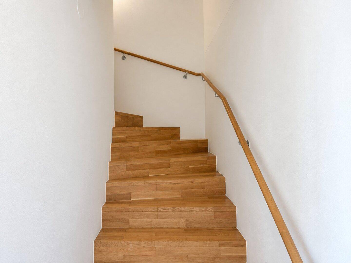 Holztreppe mit Handlauf, die die verschiedenen Ebenen der Wohnung verbindet.
