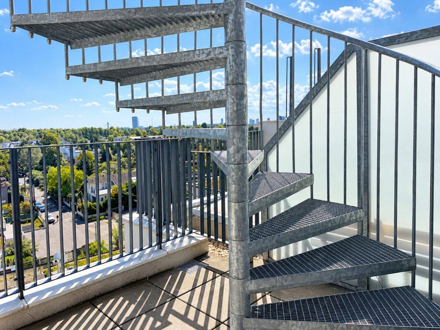 Metall-Wendeltreppe auf der Dachterrasse mit Blick über die umliegende Bebauung.