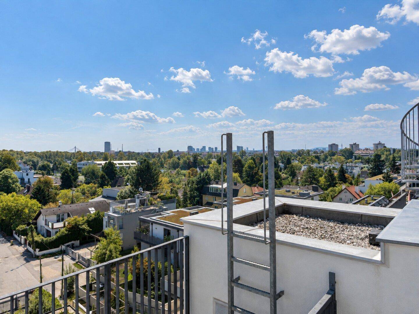 Weitläufiger Blick von einem Dach über die Stadt und die grüne Umgebung.