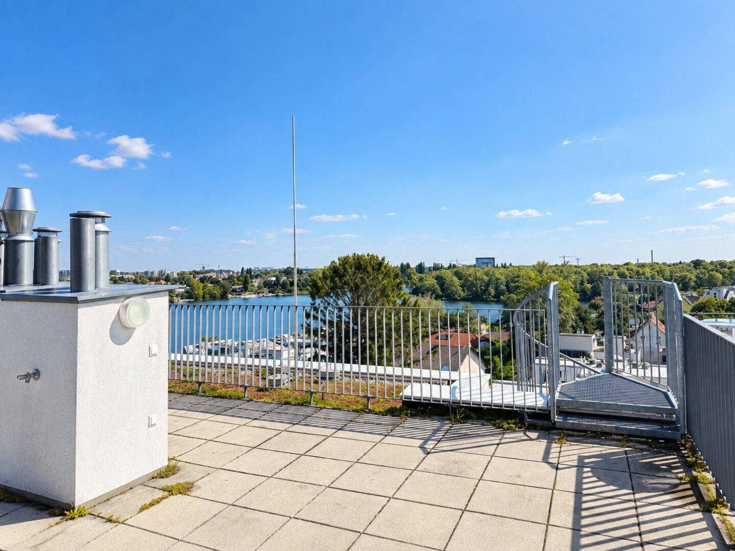 Dachbereich mit Lüftungsschächten und weitem Blick auf den See und die Stadt.