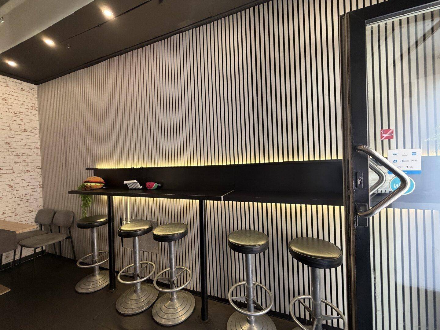 Sitzbereich eines Burger-Restaurants mit Holzwandverkleidung, Bartresen und Hockern.