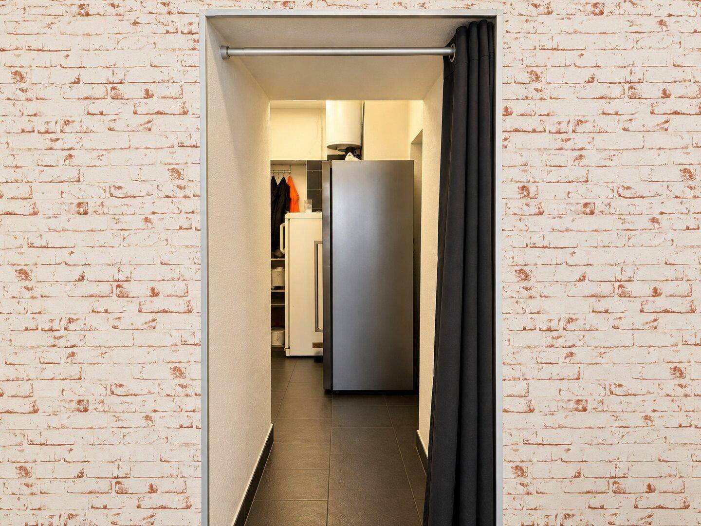 Durchgang zu einem Lagerraum mit Kühlschrank und Vorhängen, um den Bereich abzutrennen.