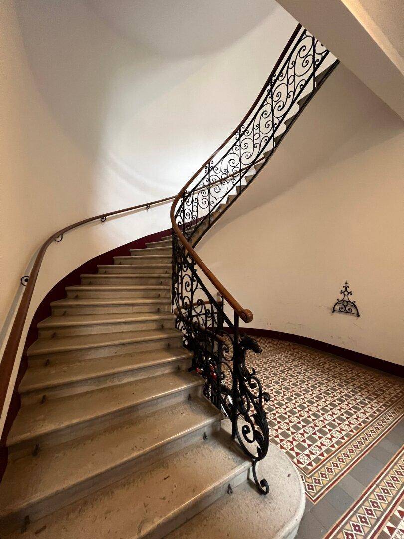 Elegantes Treppenhaus mit geschwungenem schmiedeeisernem Geländer und Marmorstufen.