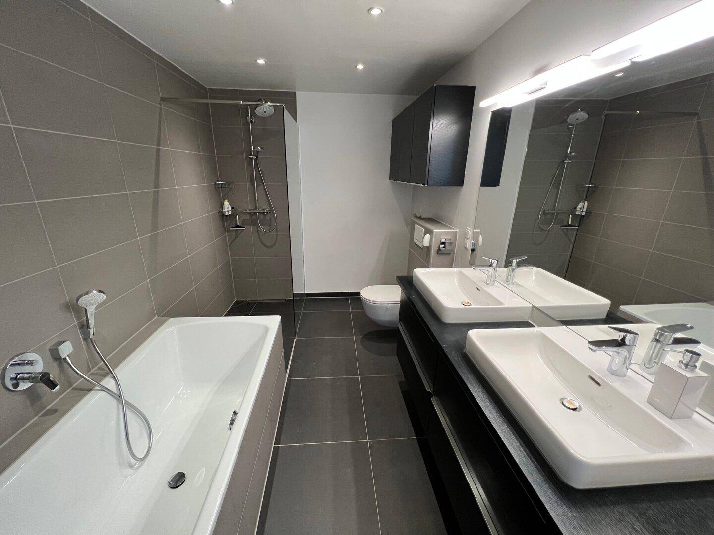 Modernes Badezimmer mit Doppelwaschbecken, Badewanne und separater, ebenerdiger Dusche.
