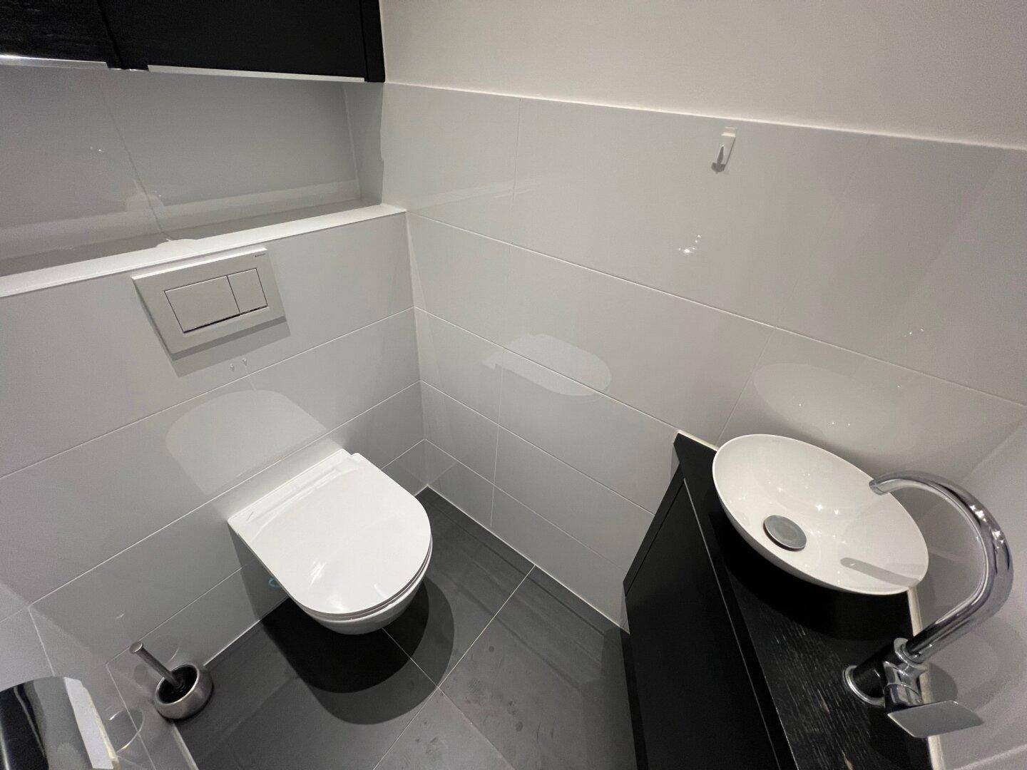 Modernes Gäste-WC mit wandhängendem WC und stilvollem Aufsatzwaschbecken.