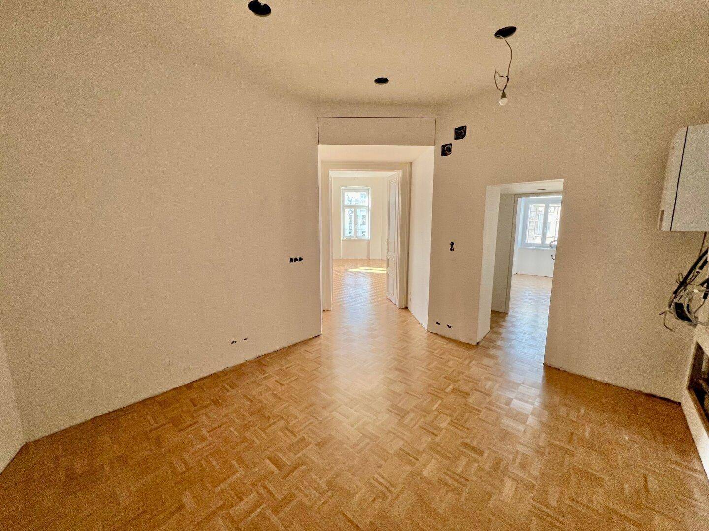 Heller Flur mit Fischgrätparkett, der zu weiteren Zimmern der Wohnung führt.