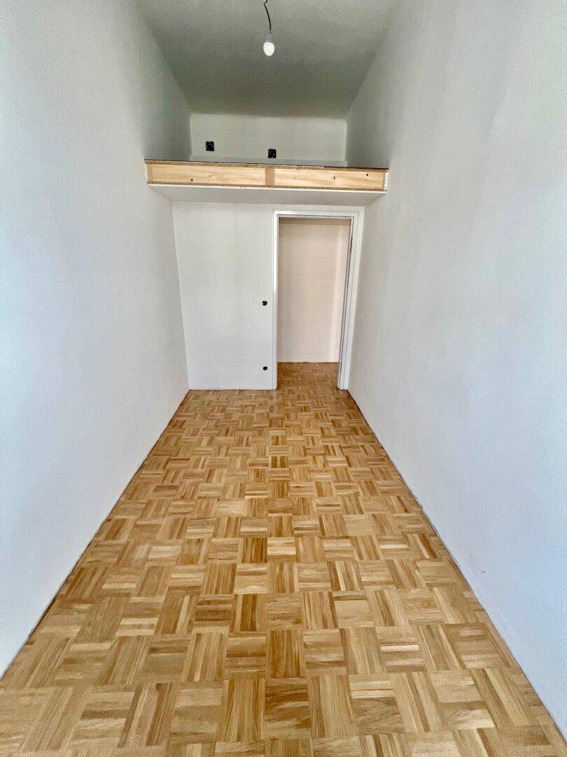 Schmaler Flur mit Parkettboden und einer erhöhten Ablagefläche oder Schlafkoje.