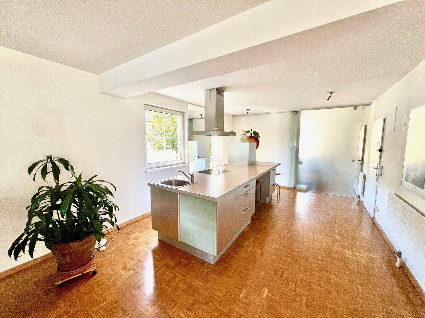 Moderne Küche mit Kücheninsel, Dunstabzugshaube und Parkettboden.