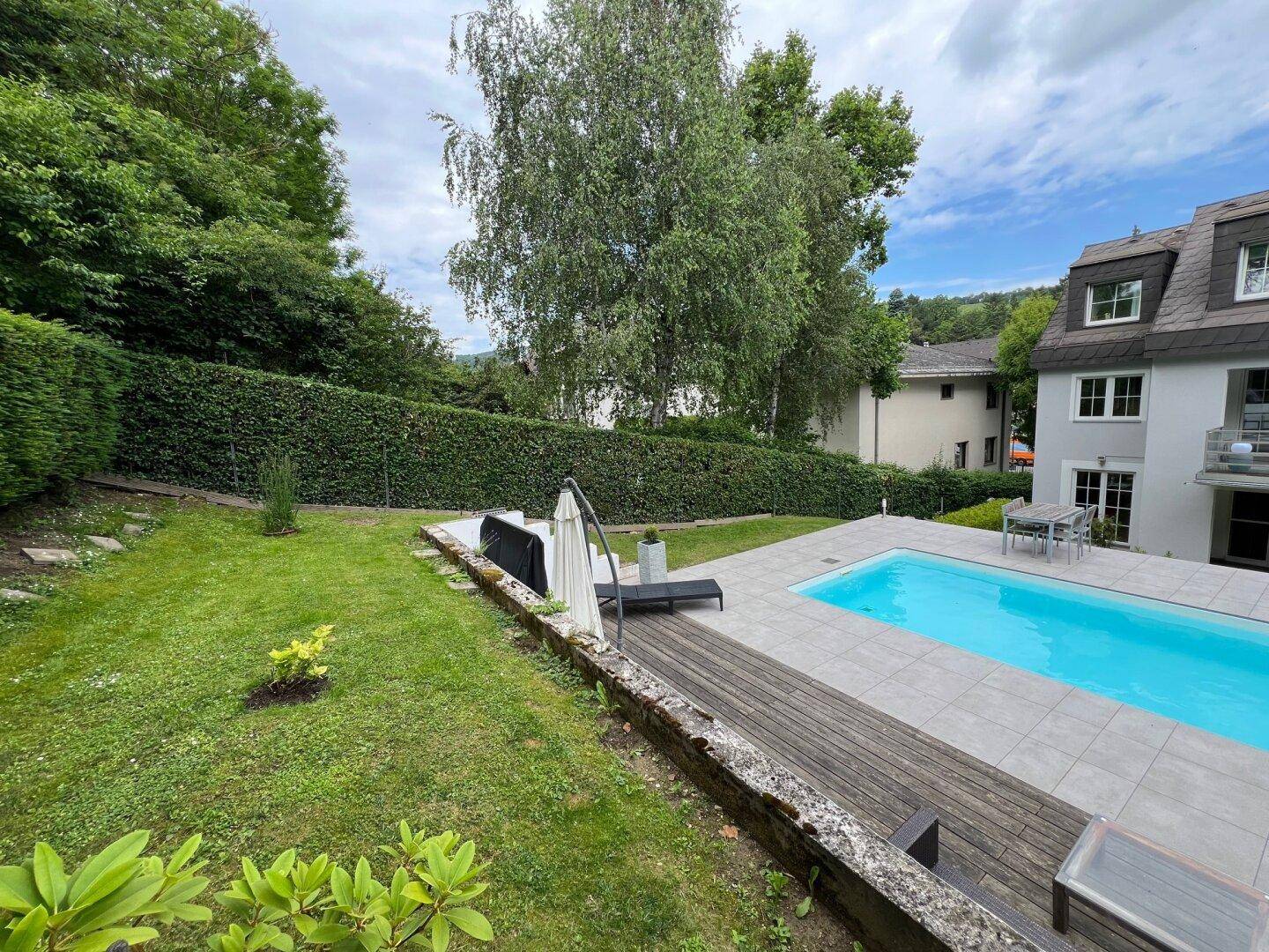 Weitläufiger Gartenbereich mit Rasenfläche, Pool und Blick auf das Haus.