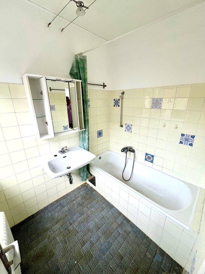 Badezimmer mit Badewanne, Waschbecken und einem Spiegelschrank, in einem älteren Stil.
