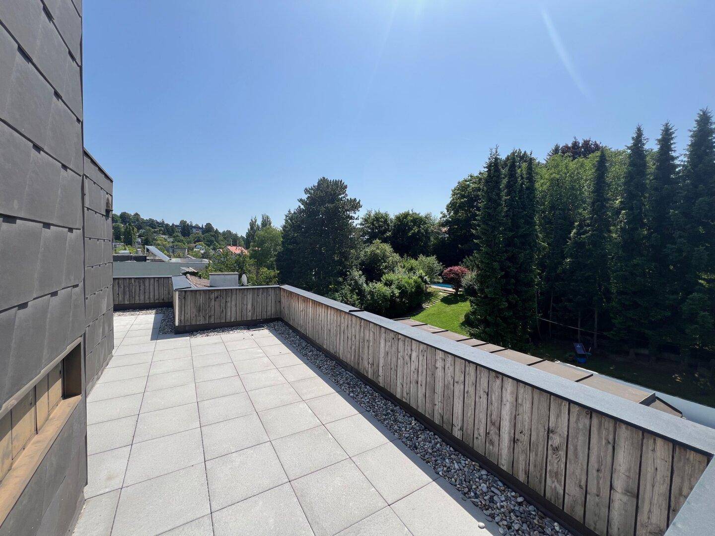 Große Dachterrasse mit Fliesenboden und weitem Blick ins Grüne.
