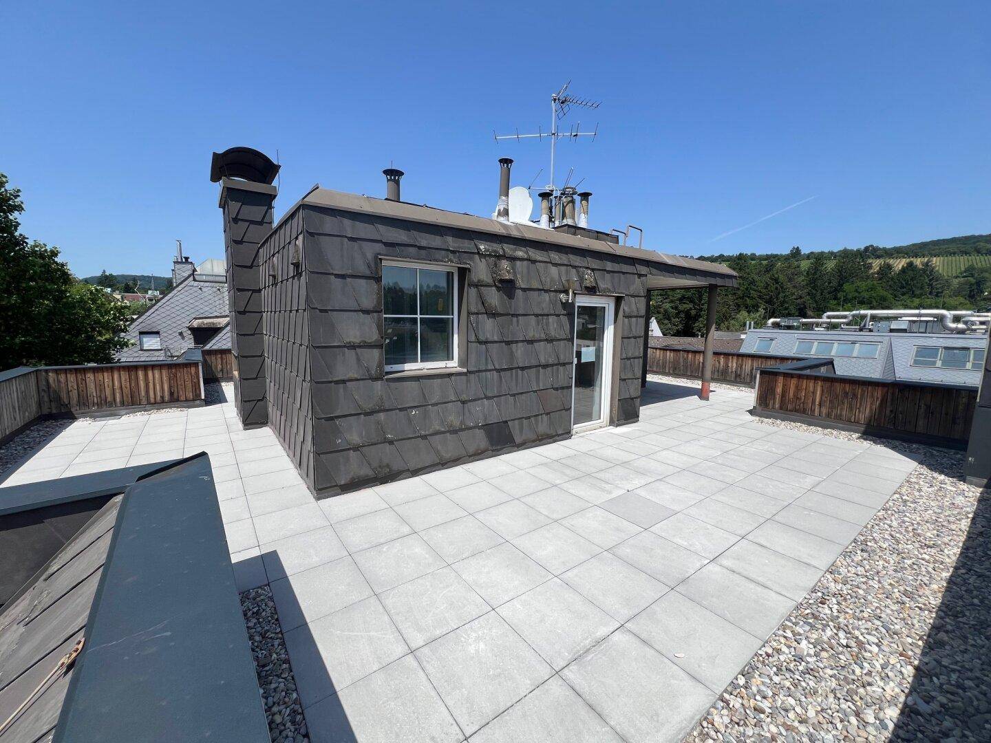 Geräumige Dachterrasse mit kleinem Aufbau und weitem Blick über die Umgebung.