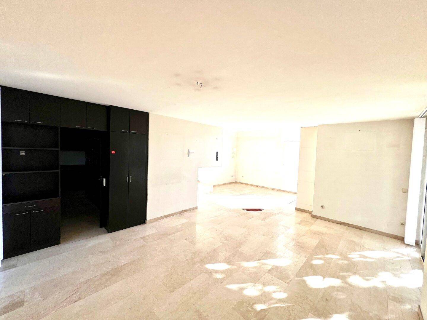 Geräumiges Wohnzimmer mit Marmorboden und eleganten dunklen Einbauschränken.