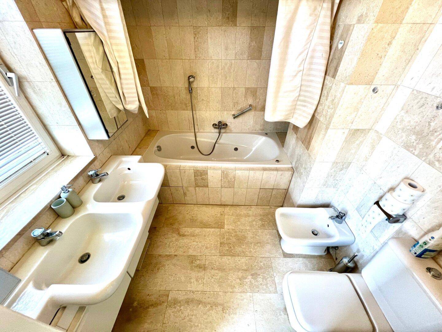 Geräumiges Badezimmer mit Doppelwaschbecken, Bidet, Toilette und Whirlpool-Badewanne.