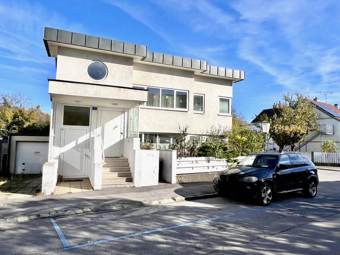 Modernes Wohnhaus mit markanter Architektur, runden und eckigen Fenstern an der Vorderseite.