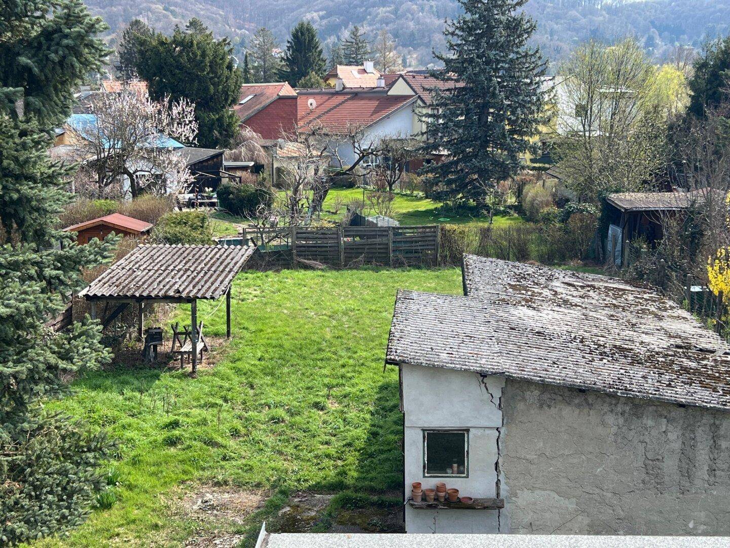 Blick von oben auf den grünen Gartenbereich mit Schuppen und umliegenden Häusern in ländlicher Umgebung.