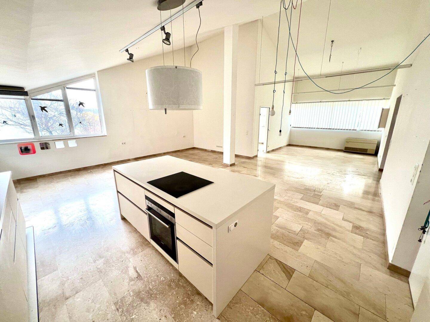 Moderne Kücheninsel mit integriertem Kochfeld und Backofen, umgeben von hellem Marmorboden.